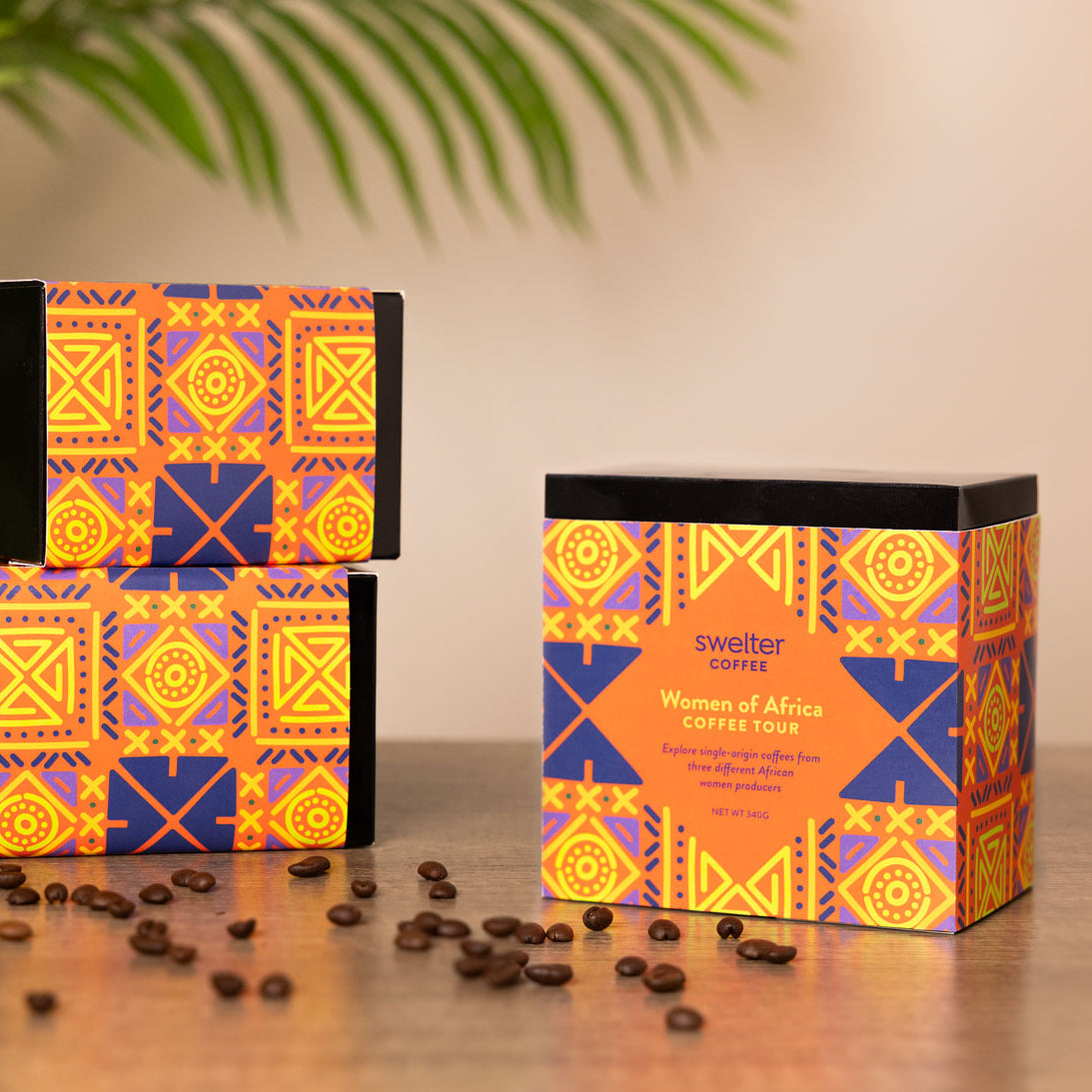 3 boxes featuring women of africa coffee on a table in front of a palm plant
