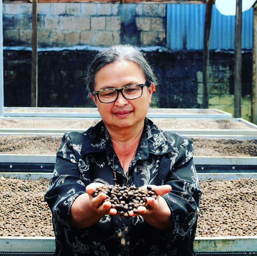 Mayra Solis holding up a handful of drying coffee cherries from her drying beds on her farm in Costa Rica