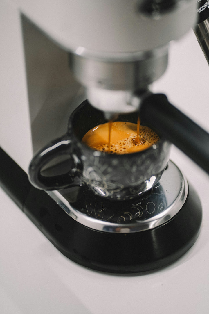 A small espresso machine brewing a double shot of coffee into a black cup