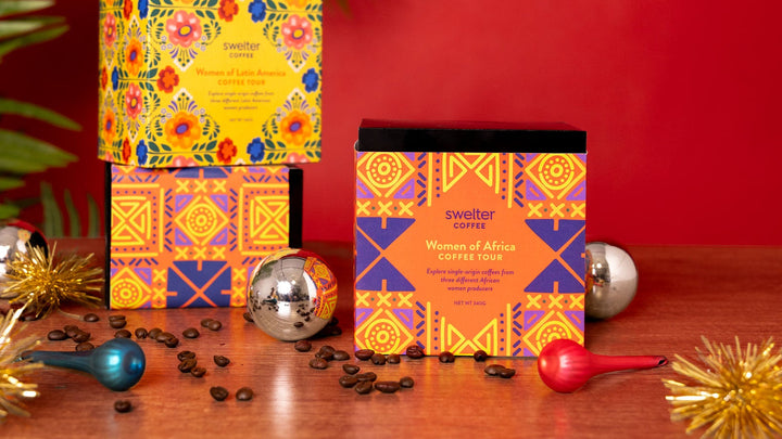 three coffee tour boxes on a table with ornaments in front of a red background