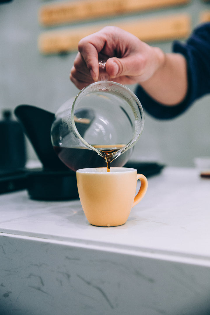 Coffee being poured into a peach colored mug